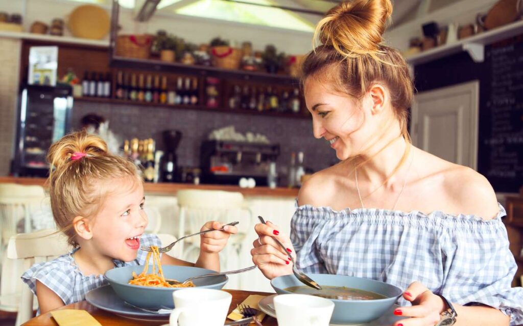 Woman and girl eating in a restaurant_14 Restaurants Where Kids Eat Free or Cheap