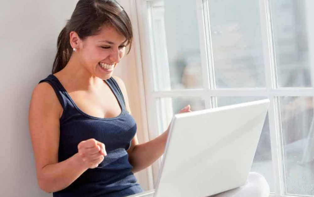 Happy woman looking at her laptop_Ways to Make Money as a Stay at Home Mum