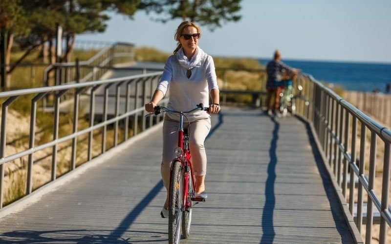 a woman ridingon a bike and crossing a small bridge