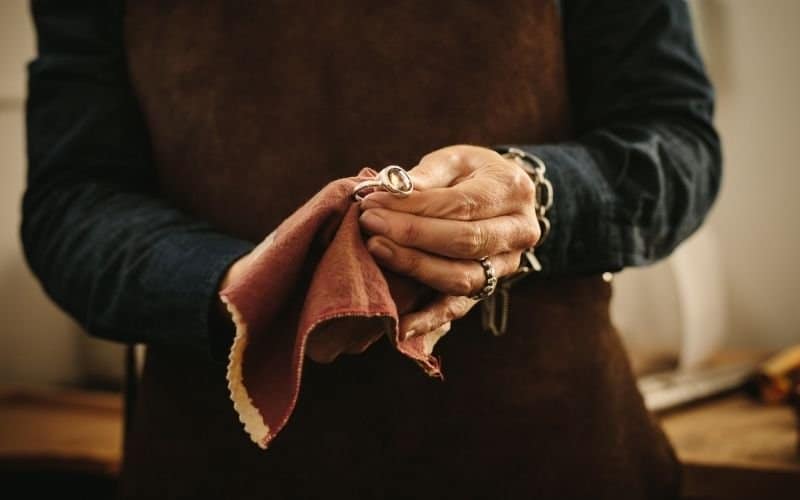 a pair of hands holding a small towel cleaning a silver ring