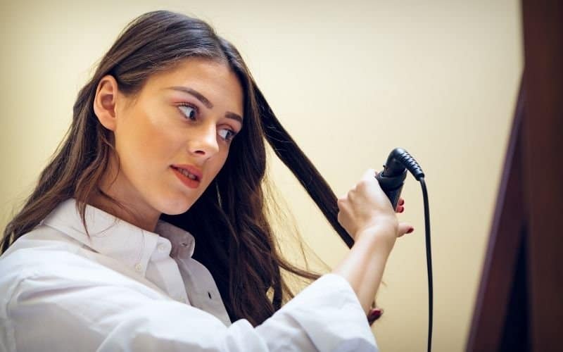 a woman trying to curl her hair with a curler she is holding