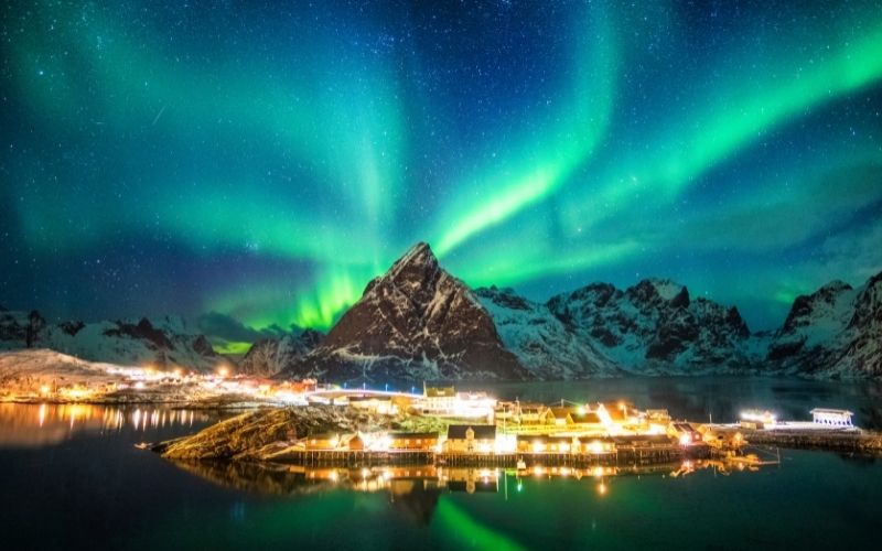 aurora borealis over mountains in fishing village norway