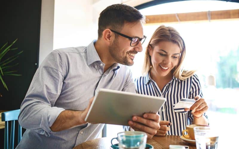 Photo showing a woman holding a card and a man holding a tablet