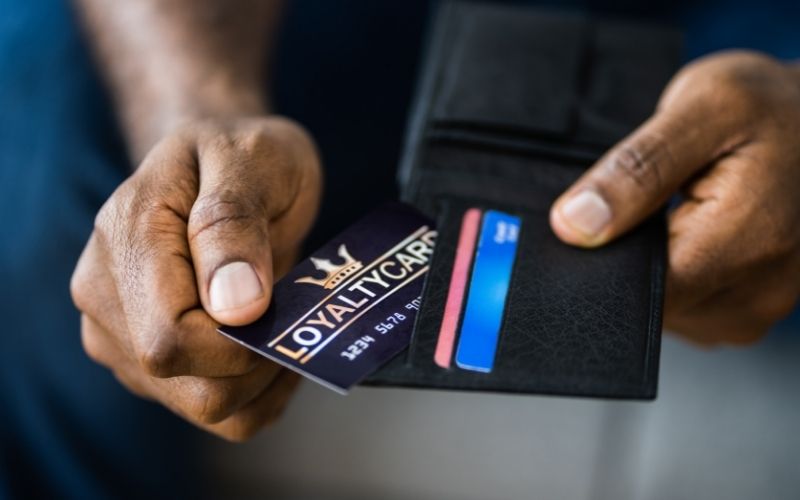 Photo of a pair of hands holding a wallet while pulling out a loyalty card 