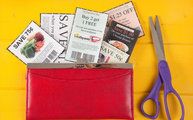 Photo of red wallet with cut out coupons beside a scissor