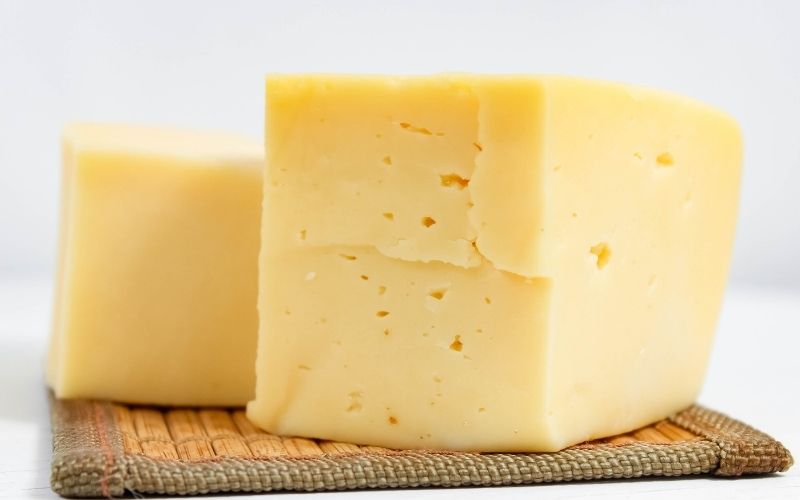 Photo of two blocks of cheddar cheese on a brown mat