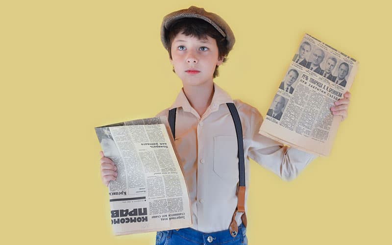 small boy holding newspaper in his hand