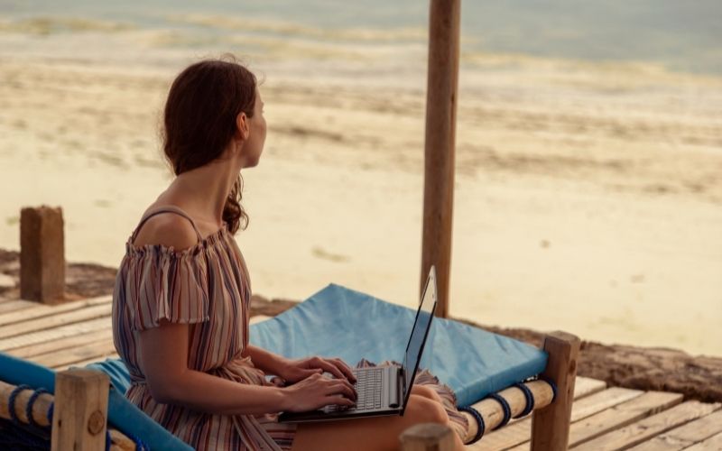 digital nomad working on laptop computer while on a beach