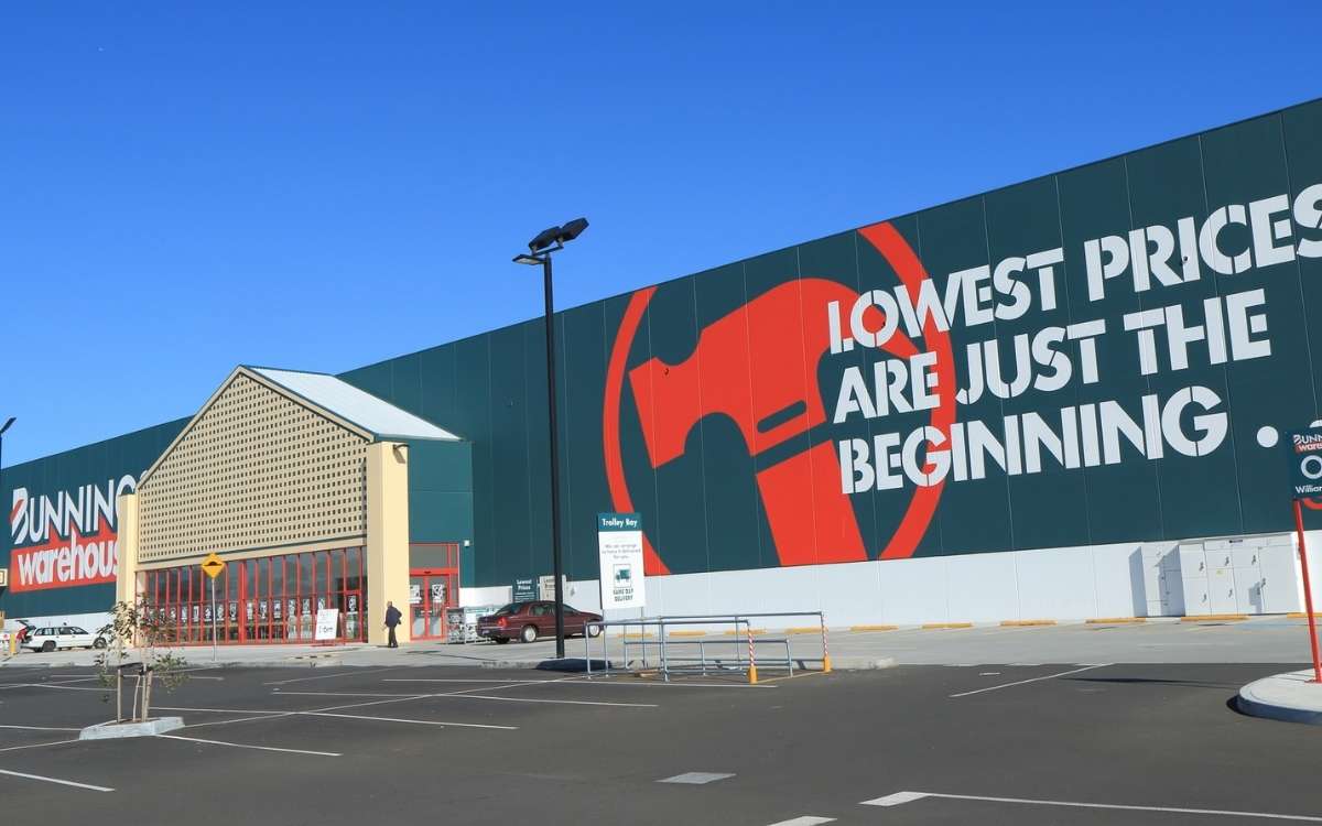 Photo showing a large building of Bunnins Warehouse withcars in parking area at the front