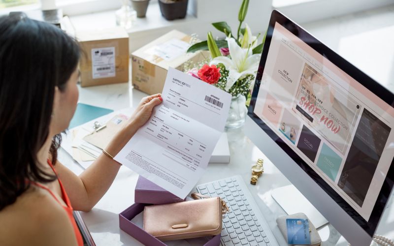 Image showing a woman holding a paper while on her desk in front of a desktop computer