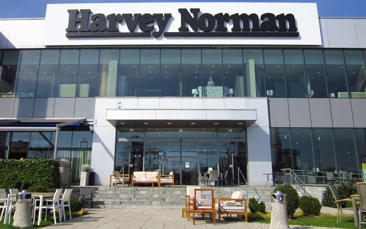 Photo of a large shopping store displaying several home furnitures and a text sign that reads Harvey Norman above the entrance.