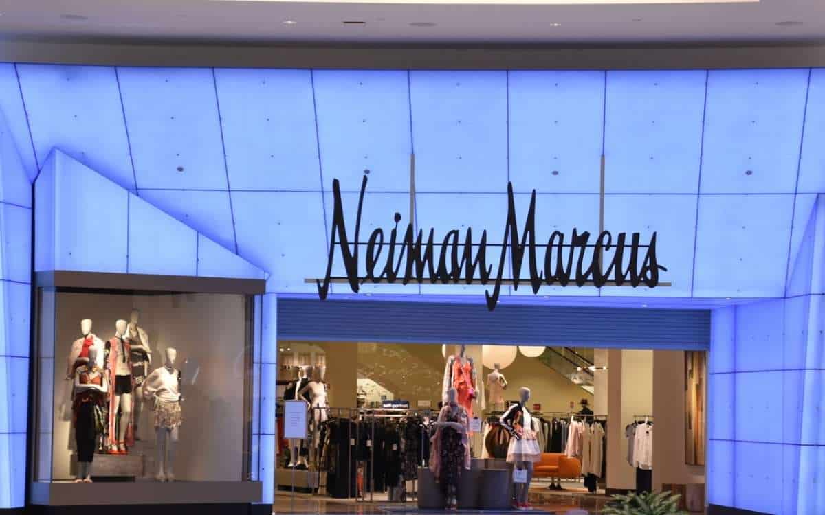 A department store with blue-colored wall with the name Neiman Marcus above the entrance with mannequins and clothes seen inside