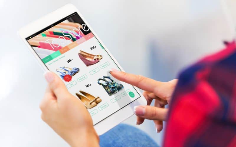 Photo of a person holding a tablet showing an online store for shoes