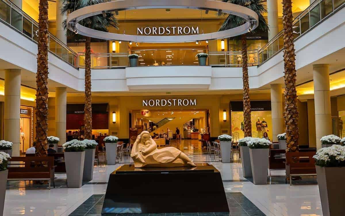 Photo of the interior of a large mall with a statue of a woman holding a baby on the fore ground and Nordstrom on the background