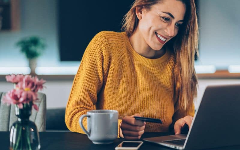 Happy woman with cedit card in front of her laptop