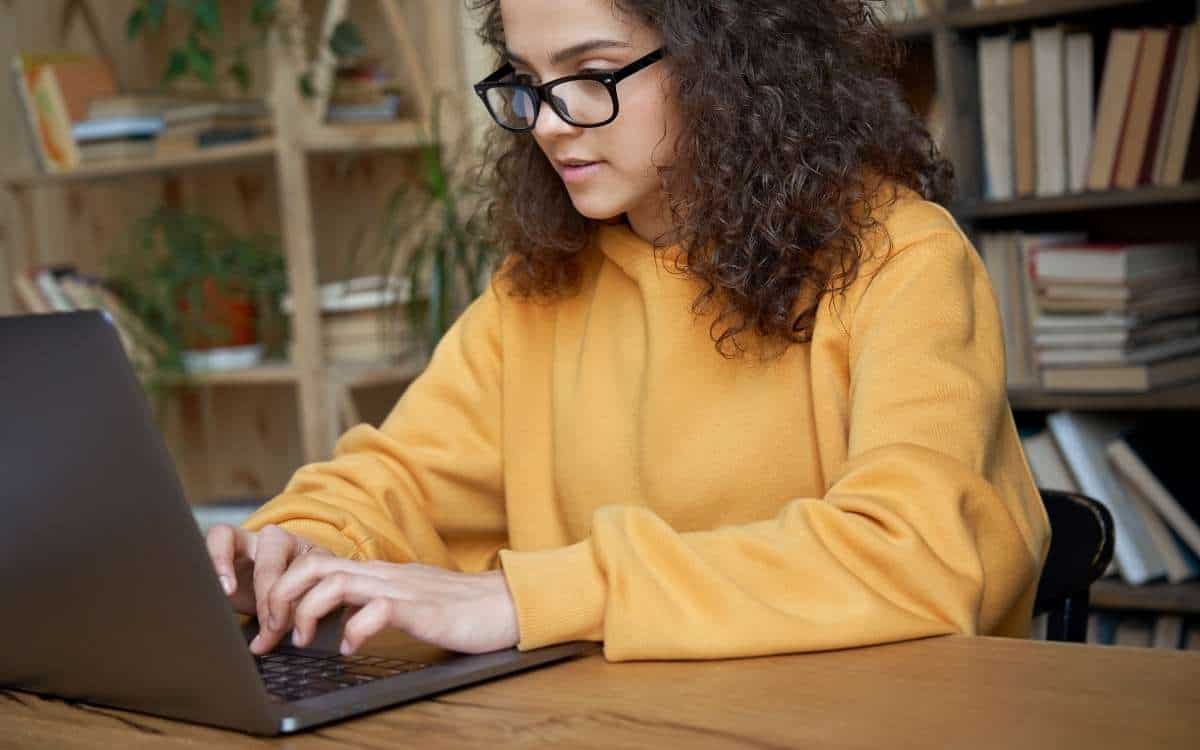 A young woman typing on a laptop on a table