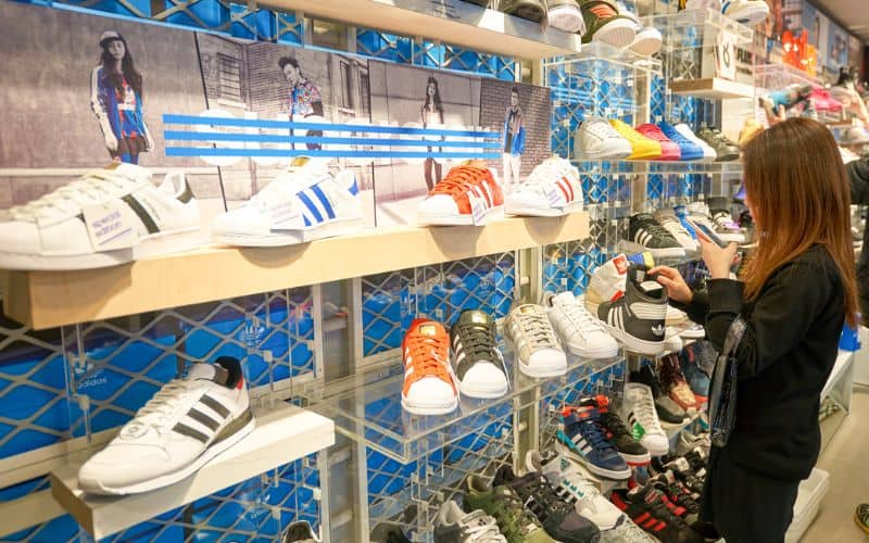 An adidas outlet shop showing a young lady checking on a shoe