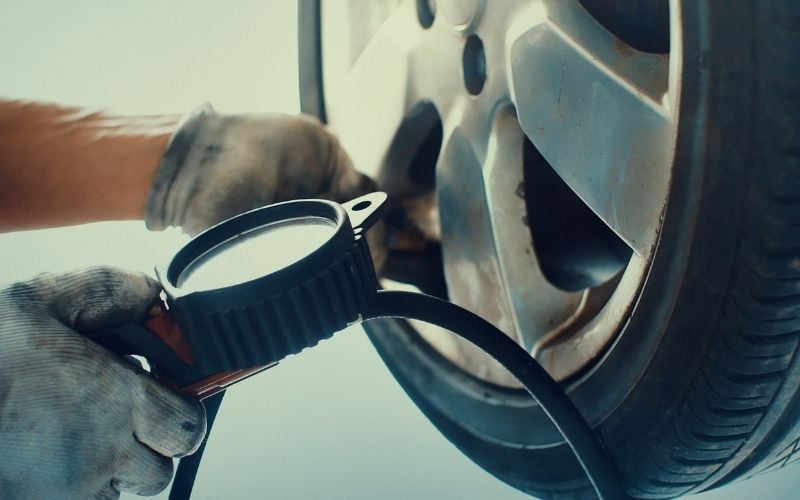 Photo of a hand holding a gauge attached to a tire