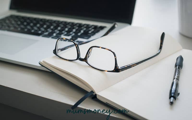 a glass and a book near a laptop