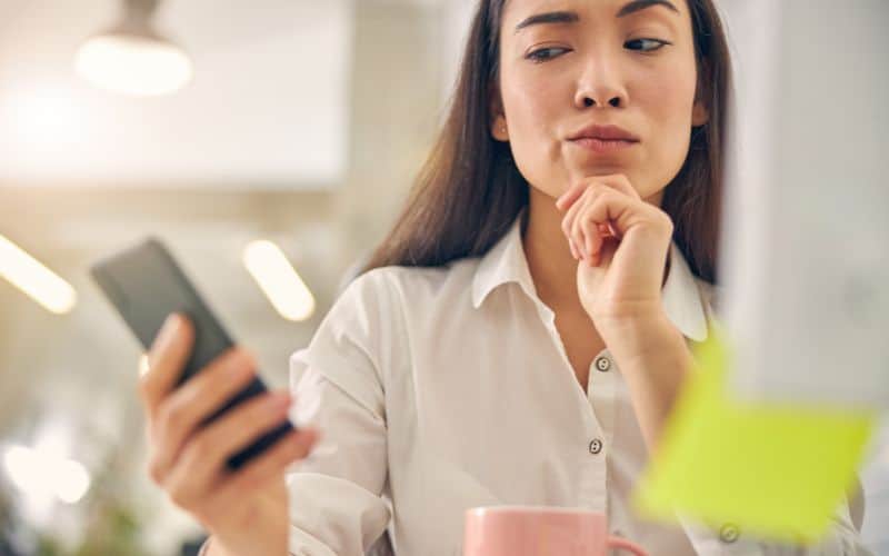 Photo of a woman looking suspiciously on her phone