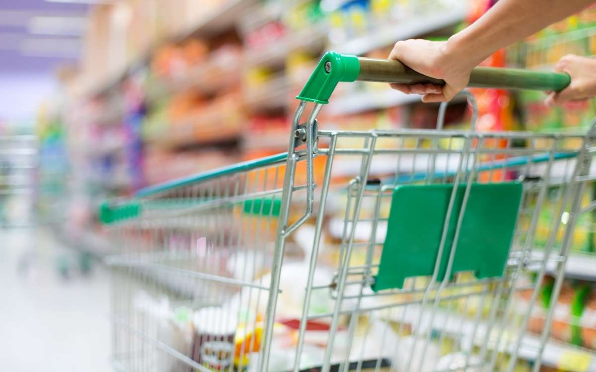 Photo a a blurred image of supermarket with a grocery cart while being pushed by a hand