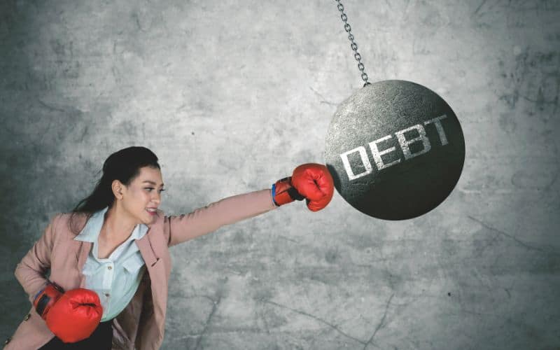 Woman punching a hanging grey ball with the debt on it_Ways to Live a Rich Life on a Tiny Budget