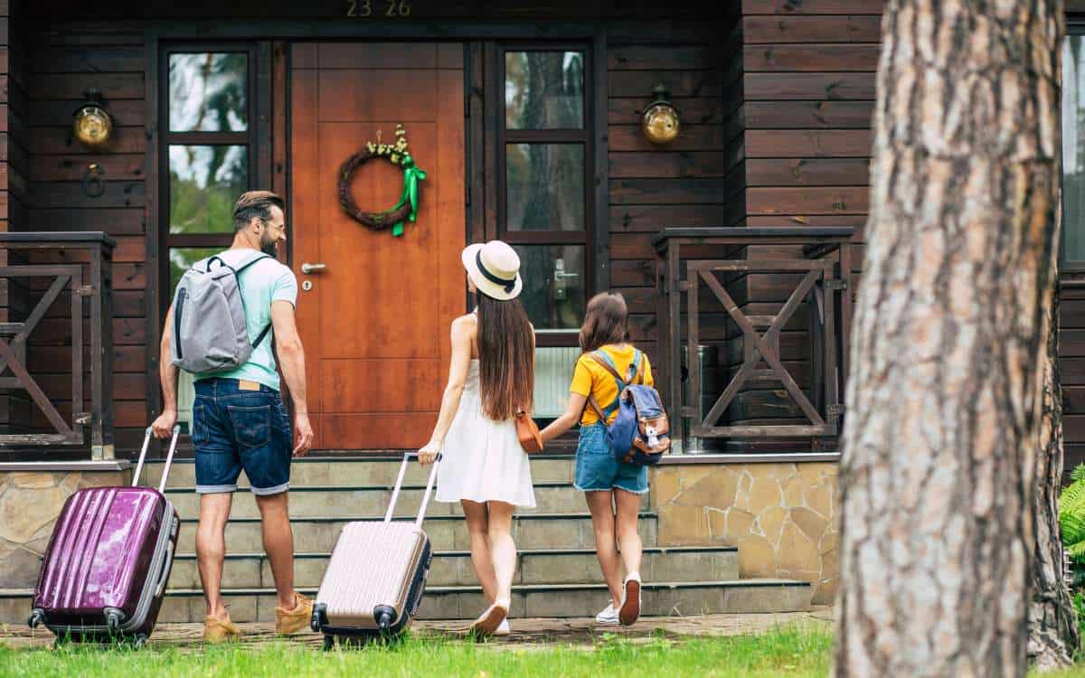 Family of 3 with luggages going into a house_What Is Home Exchanging