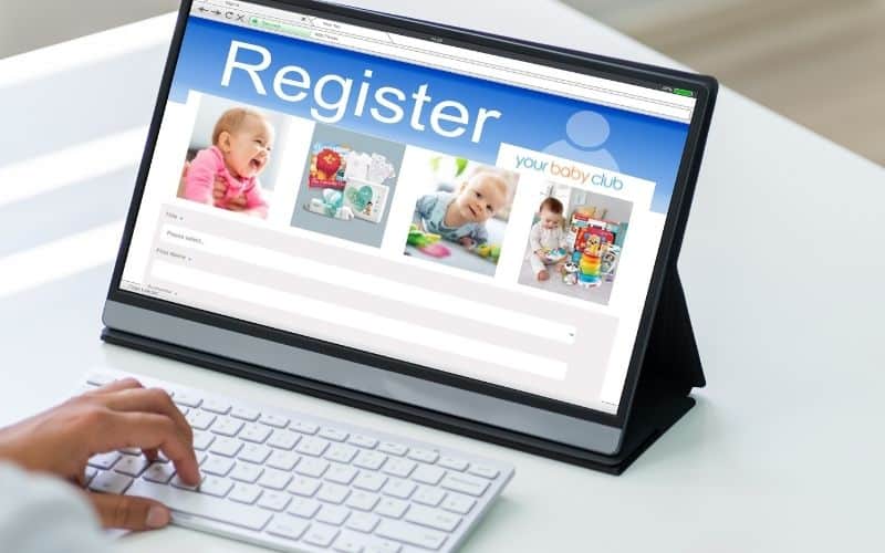 A laptop that shows registration page for Your Baby Club, with a hand on keyboard