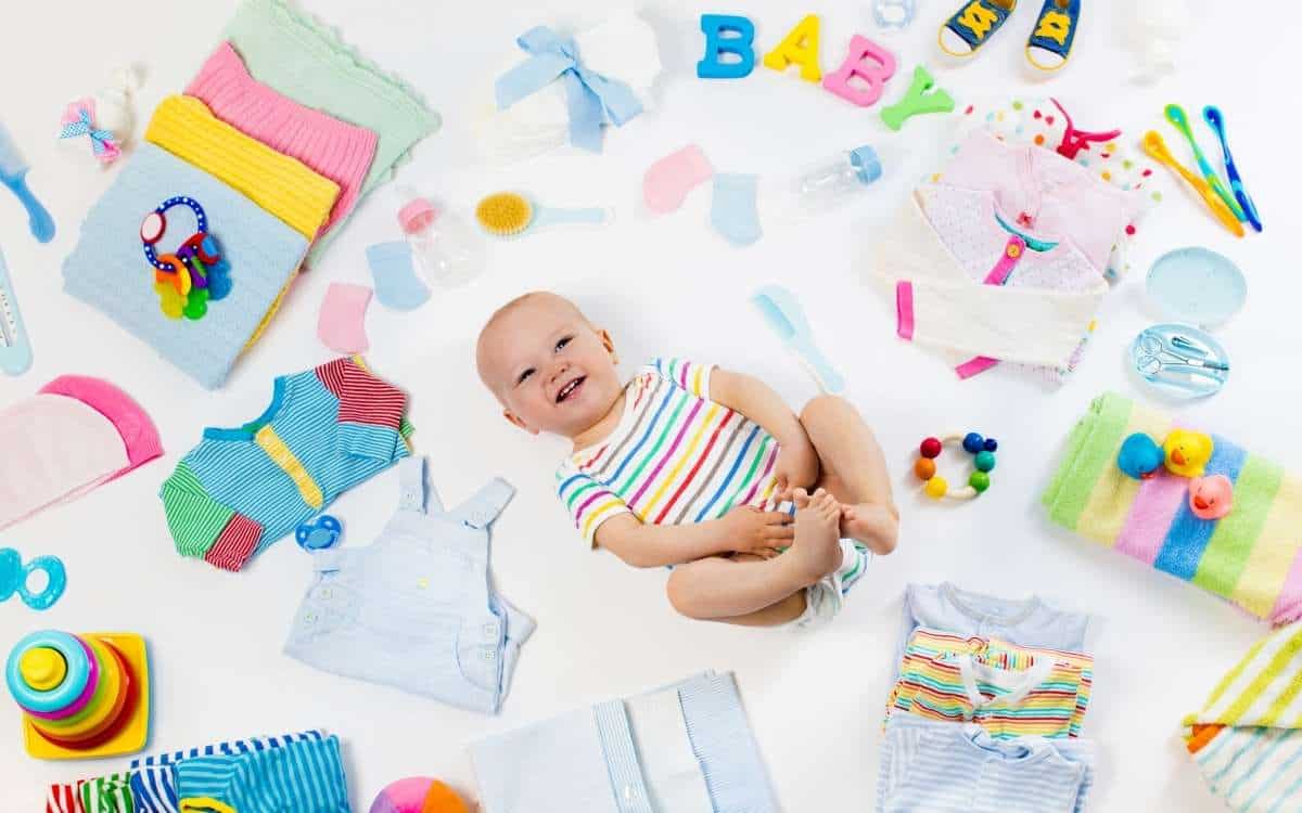 A happy baby while lying on his back with baby items around him